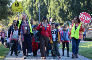 Children waiting to cross the street with volunteer crossing guard. Links to website.